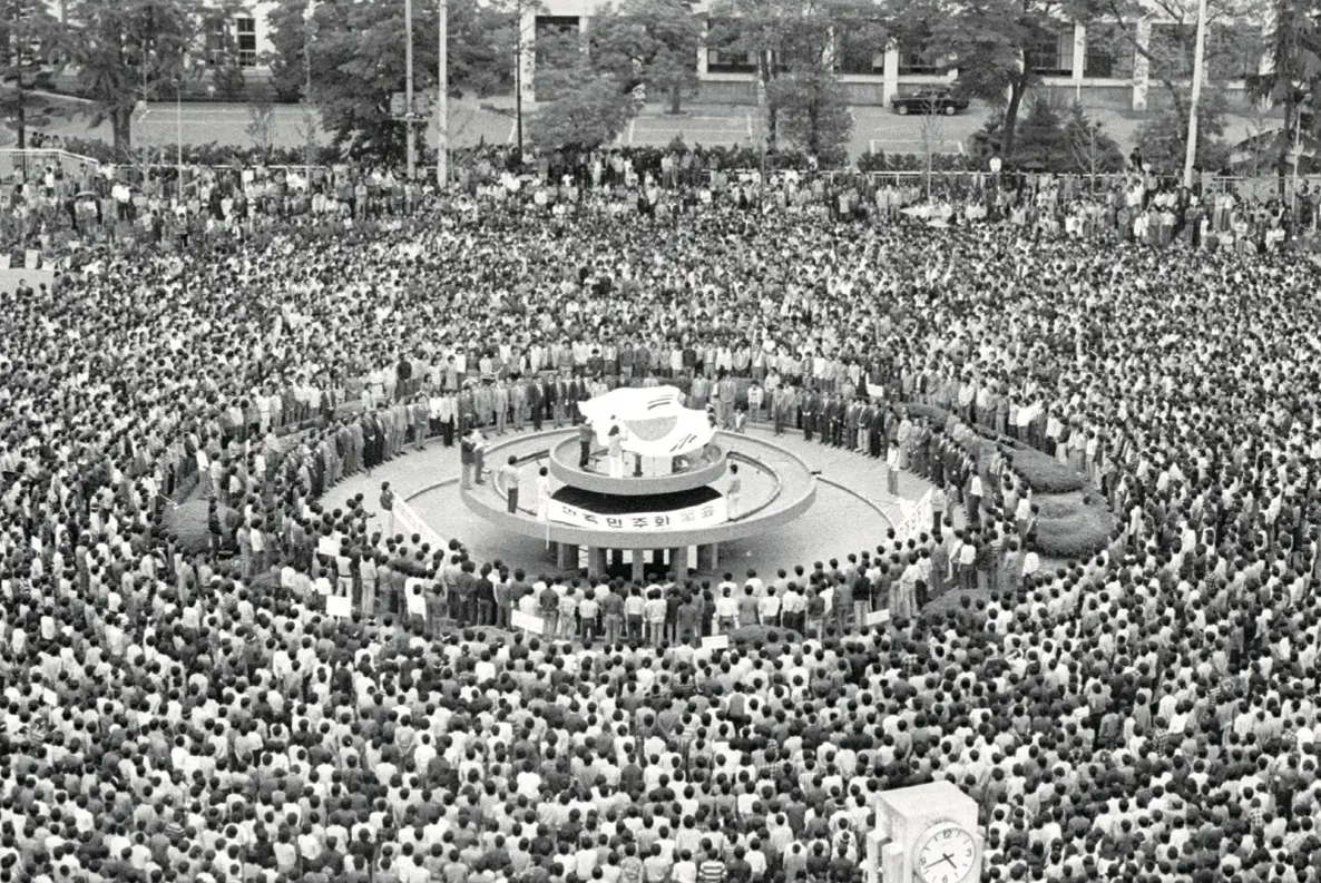 A round plaza crowded with people facing toward the center of the plaza.