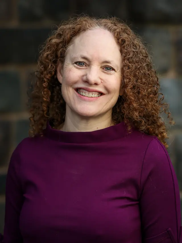Image of female with curly red hair smiling at the camera. 
