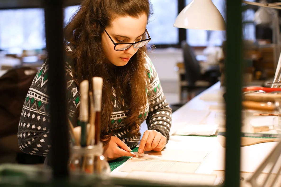 Staff member in the Conservation Lab working with delicate paper.
