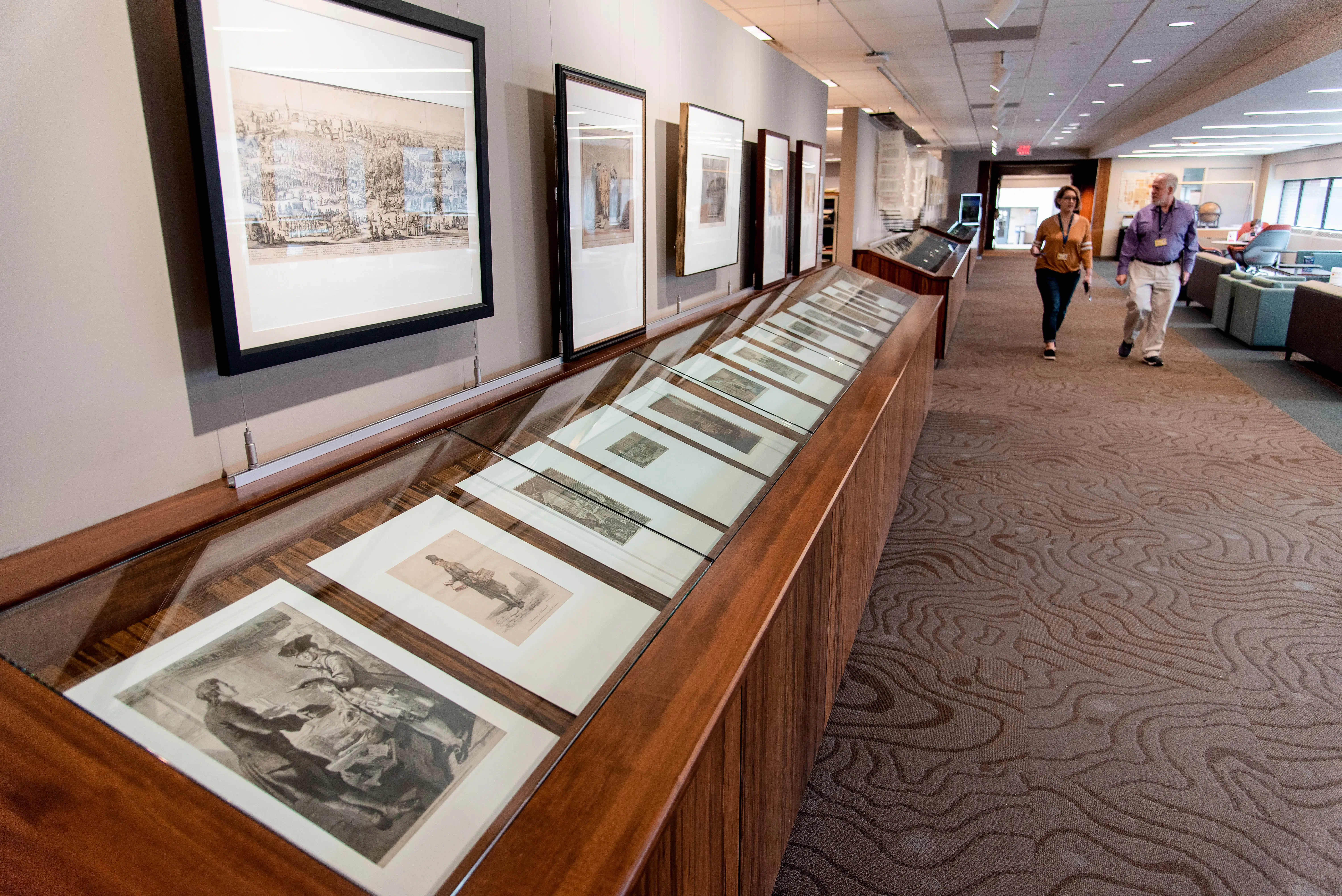 Exhibit cases and walls showcasing materials along the walkway through the Clark Library.