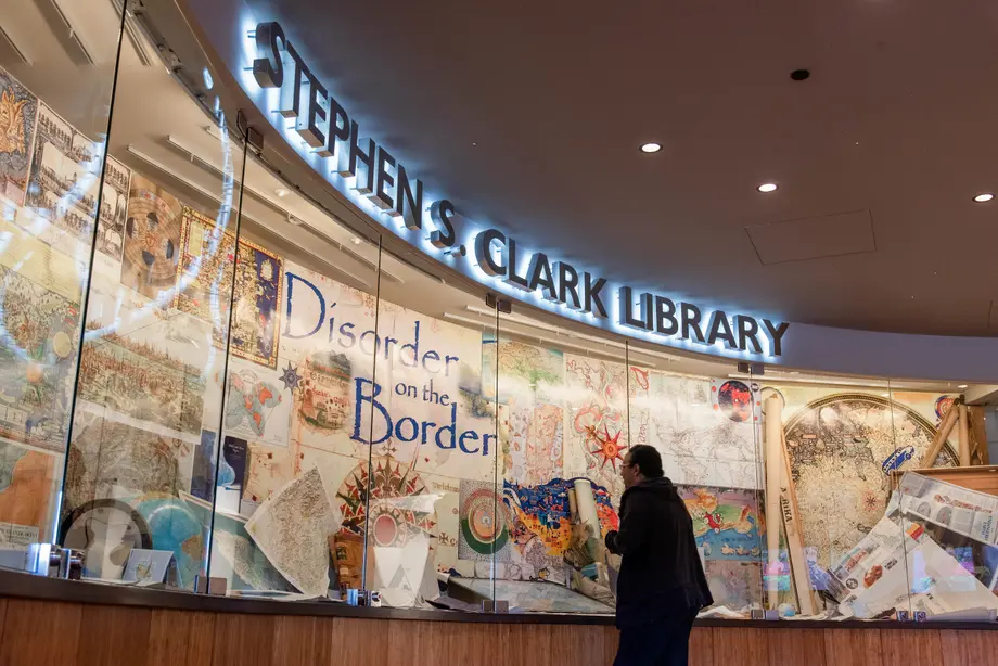 man looking at exhibit of maps and globes at the stephen s. clark library