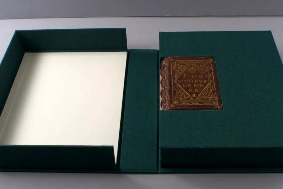 green protective box opened to show a small brown leather-bound book