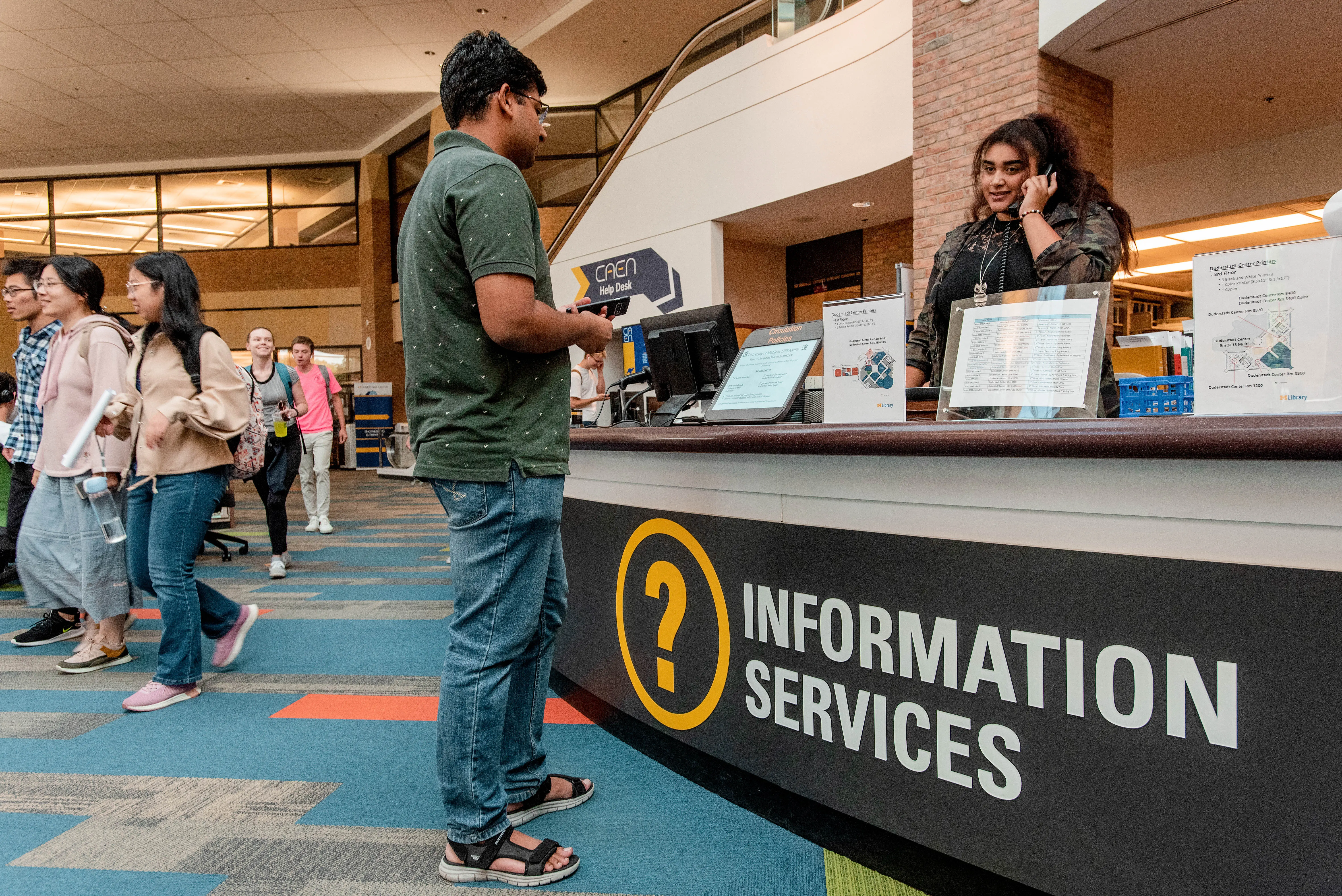 Student talking to staff behind the Information Services desk in AAEL.