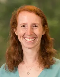 Marci Brandenburg's Photo. Female with red hair a little beyond shoulder length, smiling, wearing a light blue shirt.