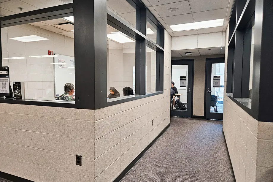 View into a hallway of group study rooms with windows on the upper half of the walls.