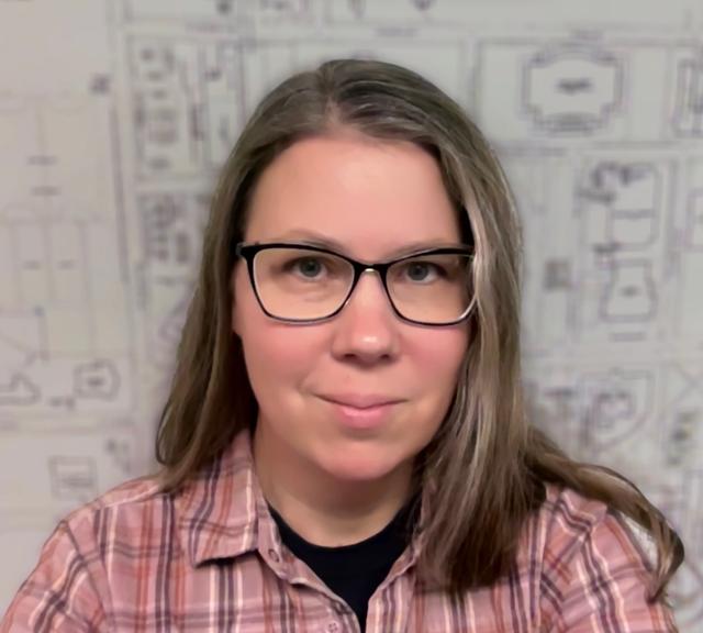 A photograph of Nicole Scholtz, a white woman with brown hair, wearing glasses, with a fuzzy black and white map as background