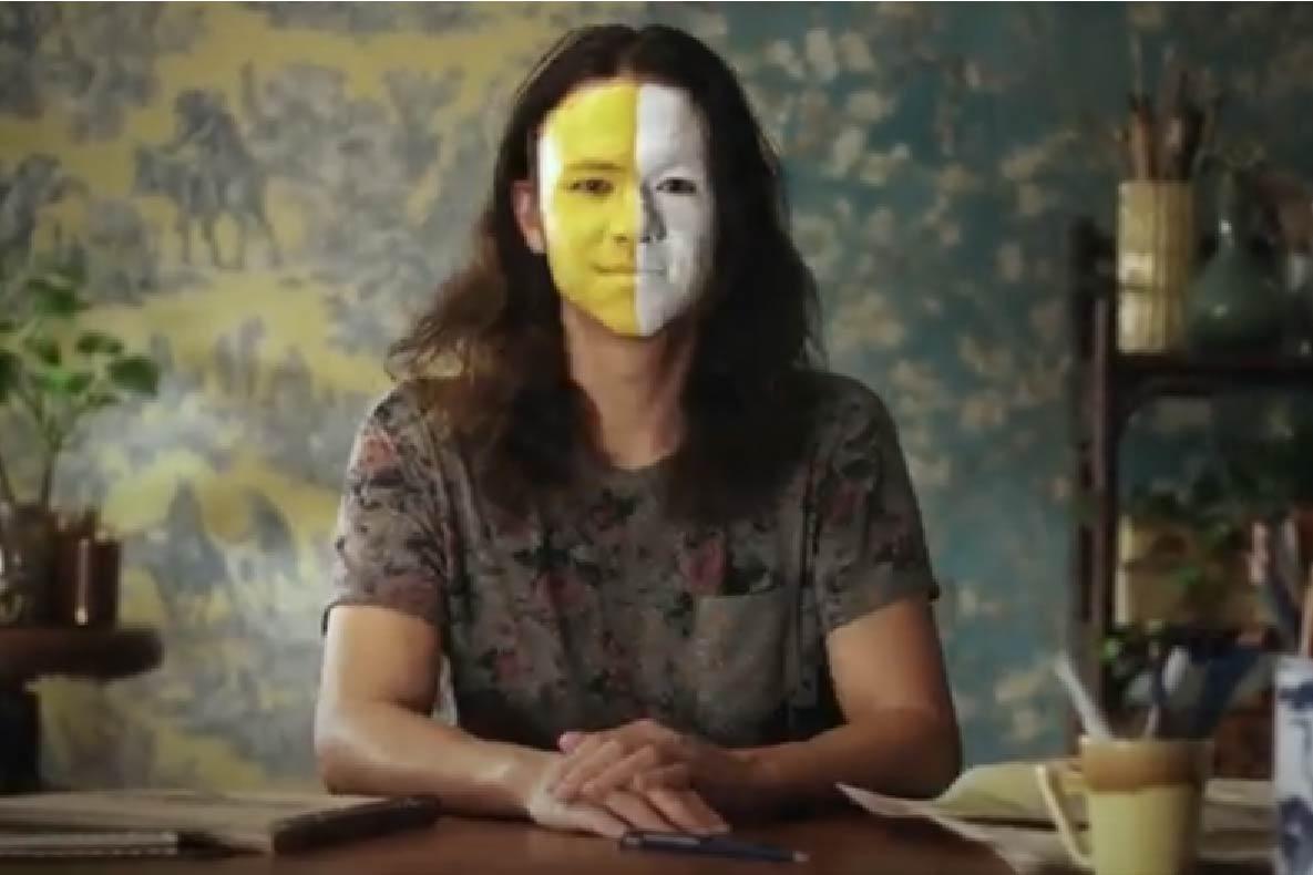 Shal Ngo, a young man, with one half of his face painted yellow and one side painted white.