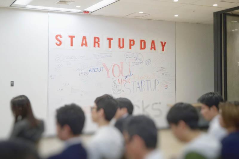 People seated in a room with "Startup Day" written on the white board.