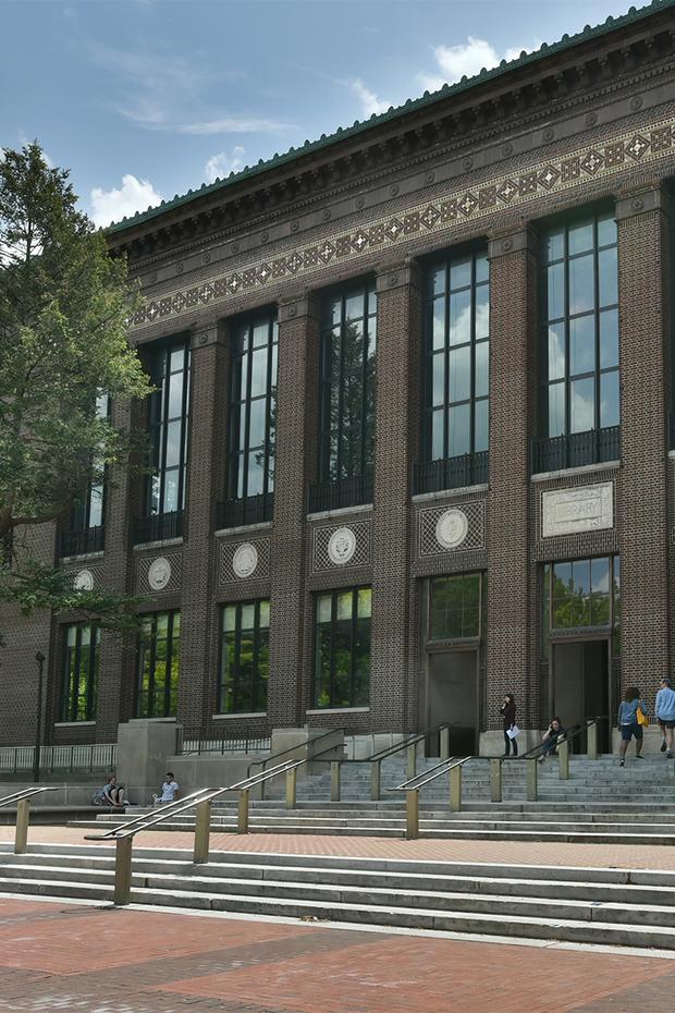 View of the Hatcher Library North entrance at an angle from the Diag with blue sky in the background.