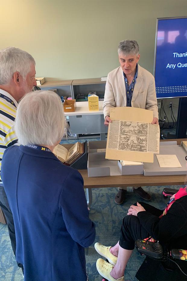 A curator showing up a rare manuscript to donors. 