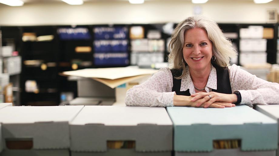 Julie Herrada looking over a row of file boxes.