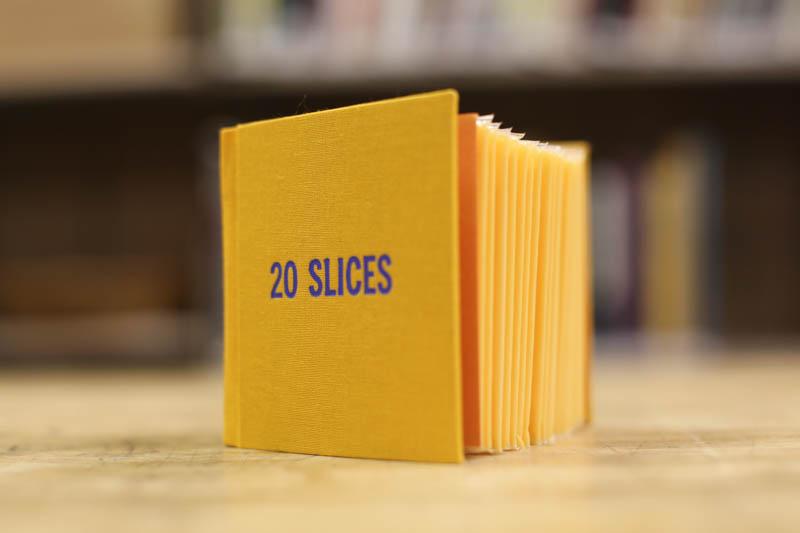 Individually-wrapped slices of American cheese bound in a yellow book cover, with the title "20 Slices".