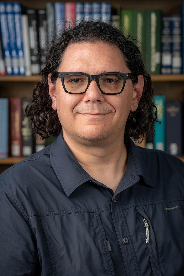 Photo of Justin Schell in front of a bookcase